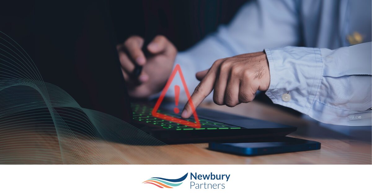 Business professional pointing at warning triangle over laptop representing data quality issues.